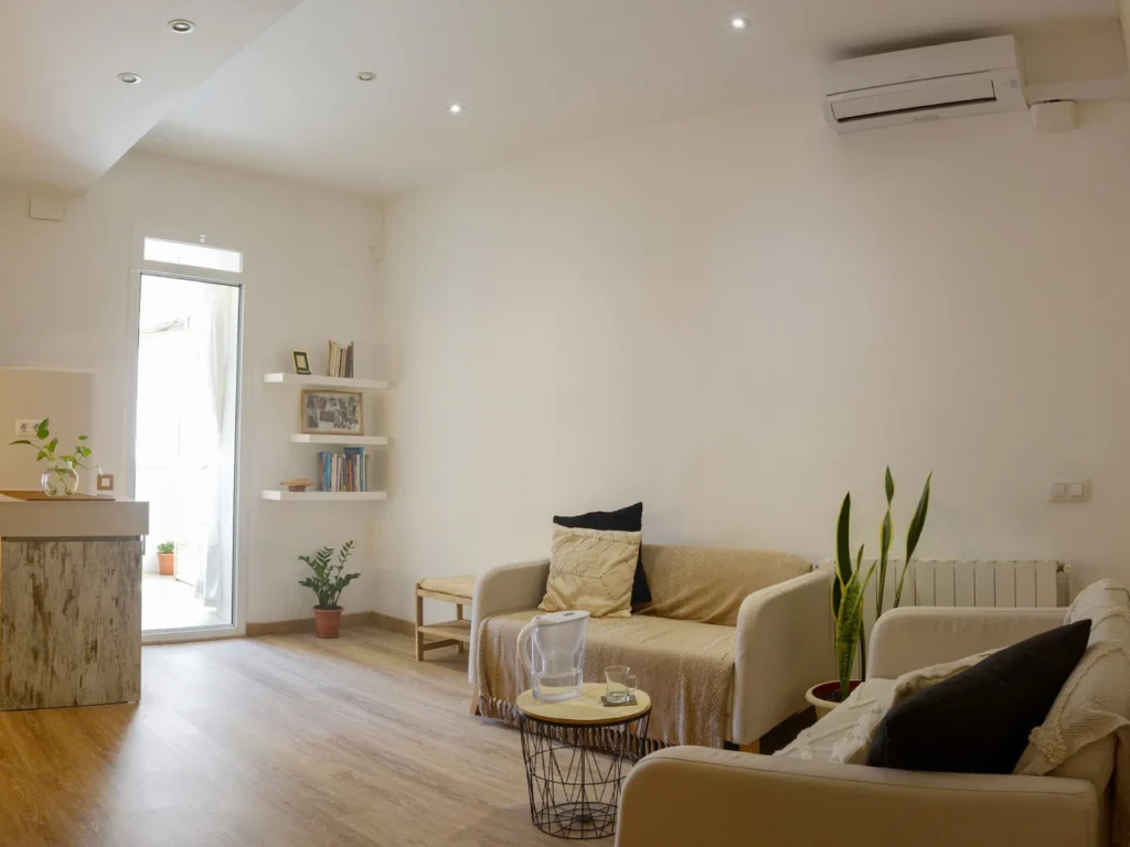 Sala de espera luminosa y acogedora con sofás, plantas y estanterías, ideal para aterrizar antes de una sesión de masaje consciente en 'donde los yayos de barcelona'