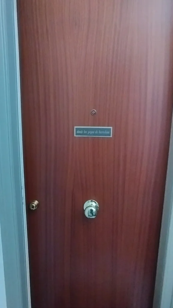 Vista frontal de la puerta del piso, con el pequeño rótulo de Donde los Yayos de Barcelona.