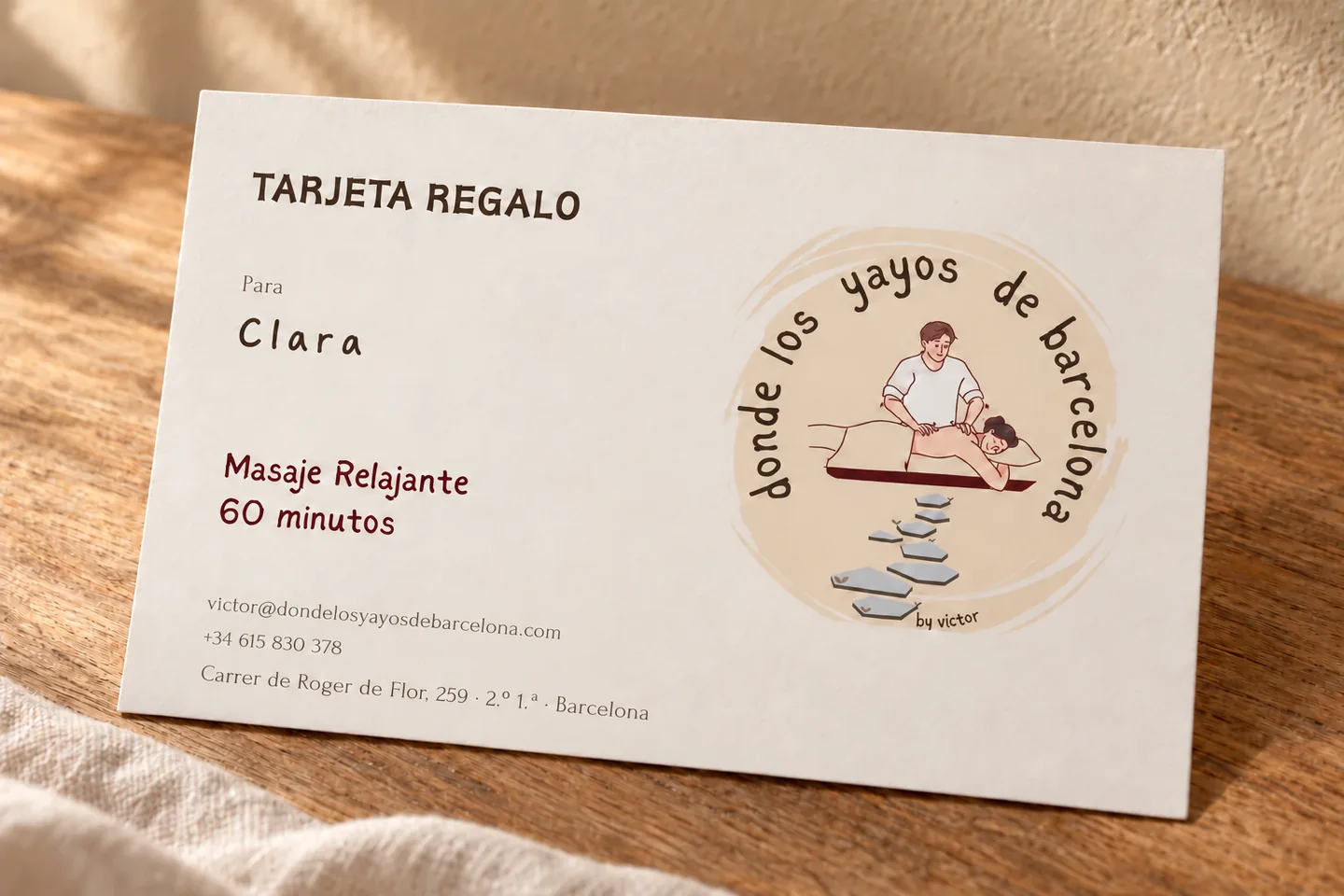 Ejemplo de tarjeta regalo de masaje para Clara sobre una mesa de madera.